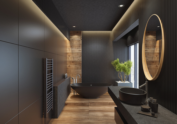 contemporary minimalist bathroom with black wooden walls and large grey matte and wood effect tiles.  round mirror with wooden frame is on the wooden black wall.  round grey stone washbasin and stainless steel basin tap is on top of the grey stone vanity unit with three drawers. freestanding black stone bathtub and floor mounted inox tap is on a platform with wood effect tiles.  long floor tiles with wood effect. black ceiling with strip cove lighting and embedded spotlights.  ***background is my istock image